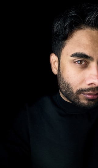 Portrait of Artan Davoodi wearing a black turtleneck against a black background